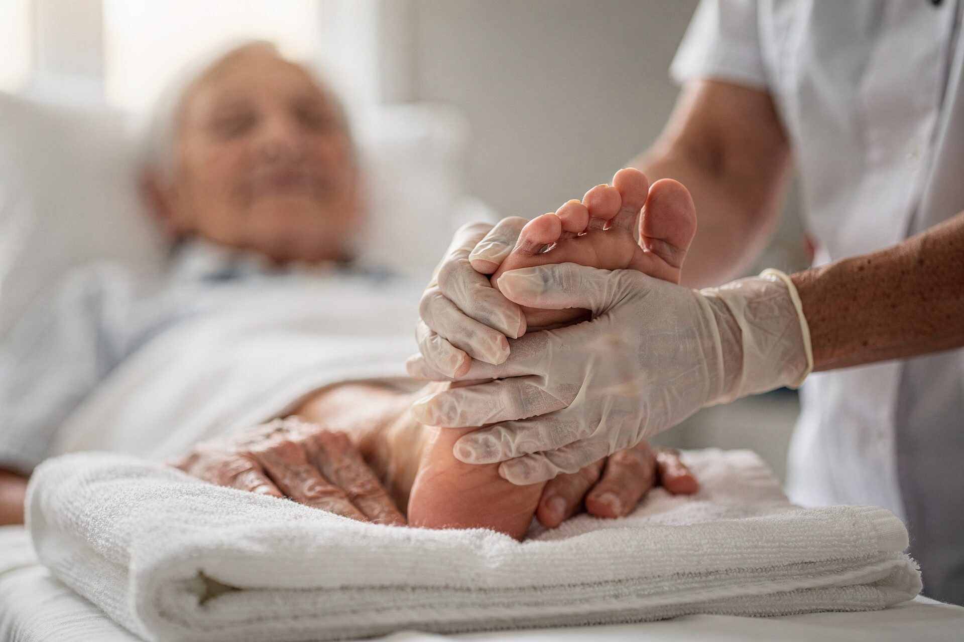A nurse holding an older patient's foot during a visit